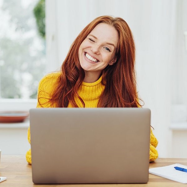 Zwinkernde Frau vor einem Laptop stöbert im usedSoft Shop