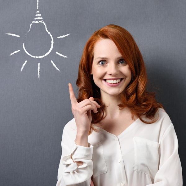 Lächelnde Frau zeigt auf eine gezeichnete Glühbirne, die Know-How zu Gebrauchtsoftware symbolisiert